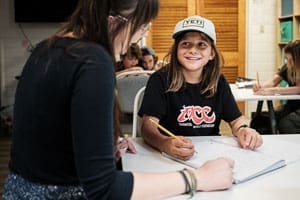 Elementary student works with teacher in small class.