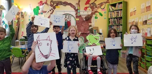 Group of kids at part time school display drawings of foxes.