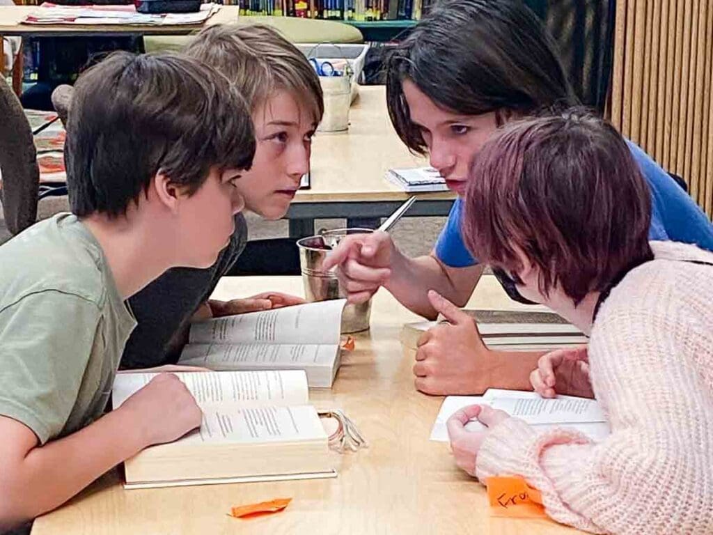 Four middle school students discuss reading at table. 