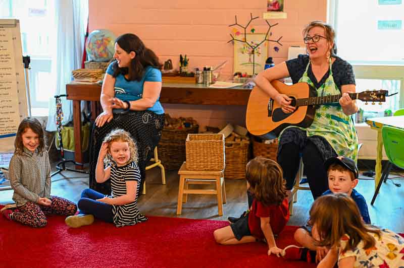 Two teachers sing along with kinder and first grade students at private school.