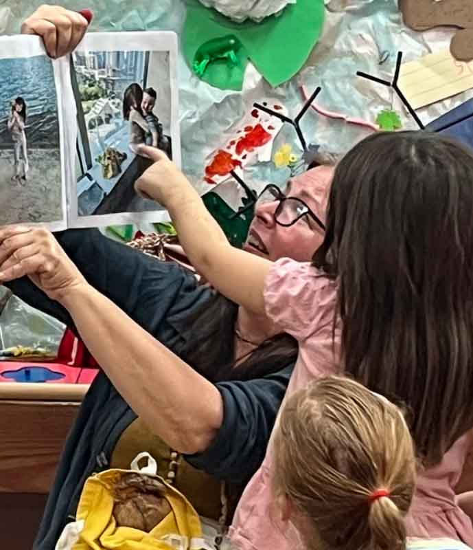 Kindergartener points to picture of herself as teacher displays book during circle time at micro school.