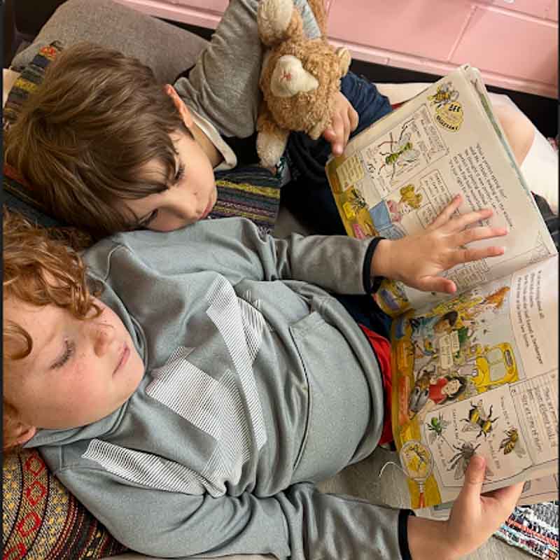 Two boys cuddle up to read a book at progressive school.