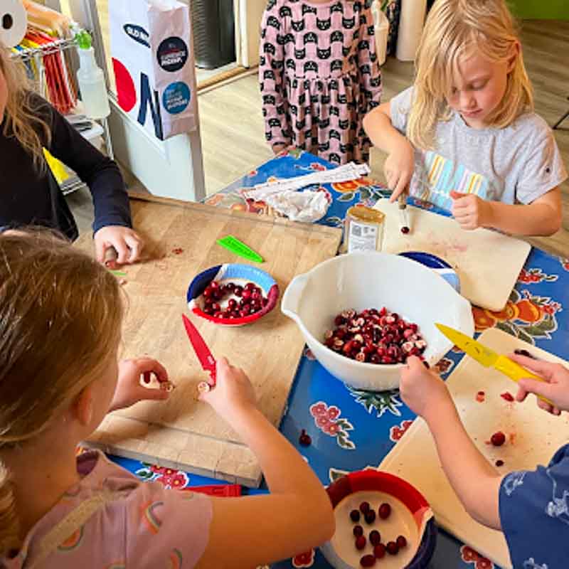 Four kids chop fruit for cooking in part time kindergarten.