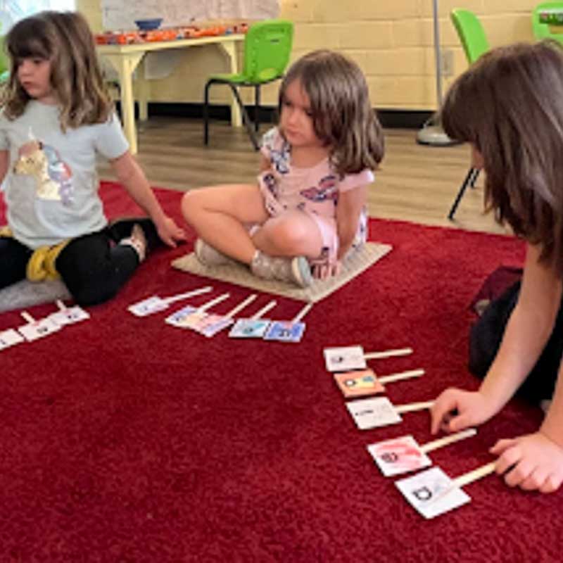 Three girls play with language manipulatives as part of hands on learning.