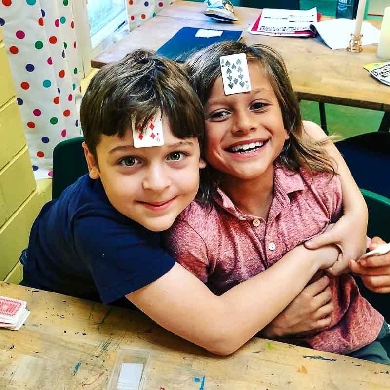 Two third grade boys laugh over math game at social emotional learning school.