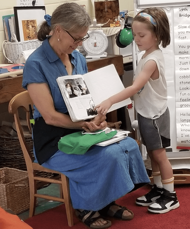 Child point at book with teacher.