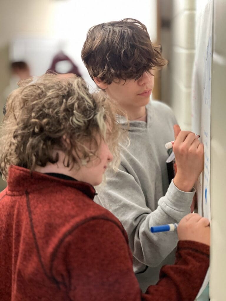 Two eighth grade students work together at board at collaborative private school.
