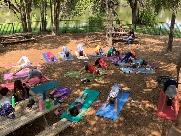 Students do yoga under the trees at homeschool enrichment program.