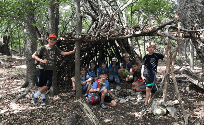 Students huddle in fort they build at nature based Friday enrichment program.