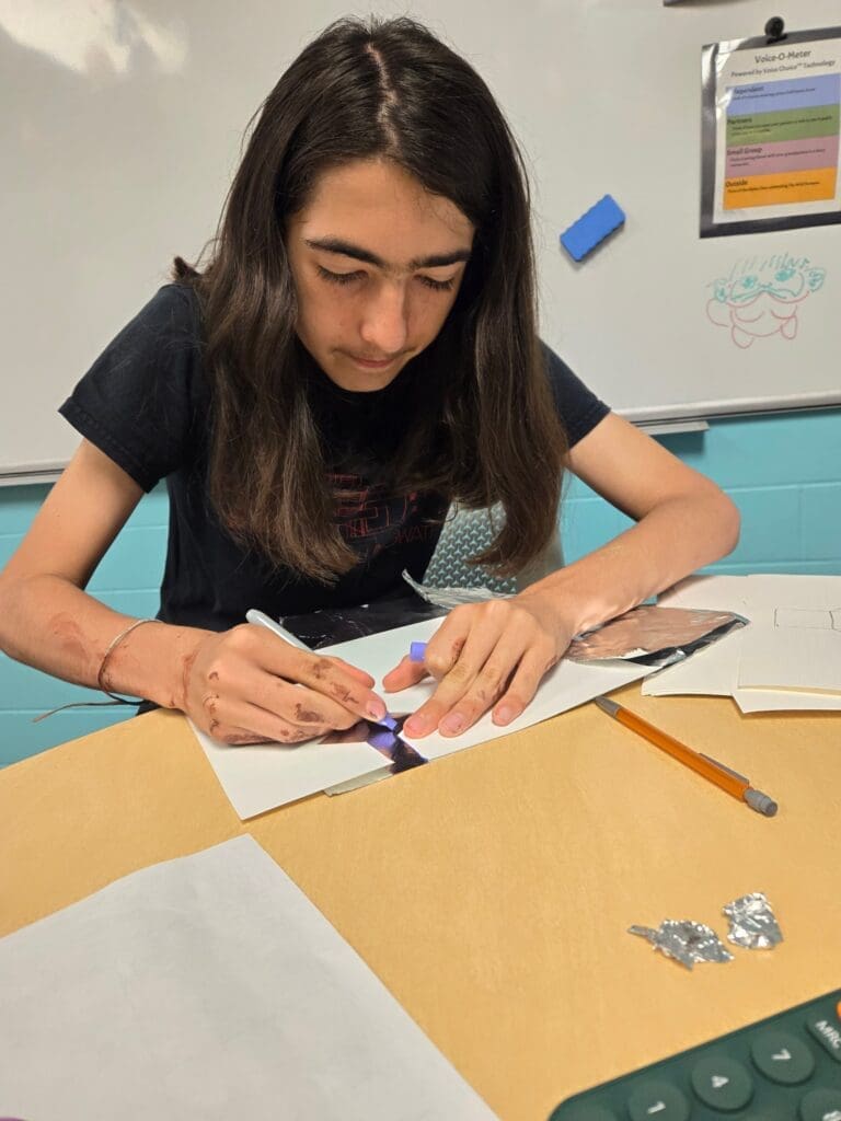 Middle school student works on math at table at alternative middle school in Austin.