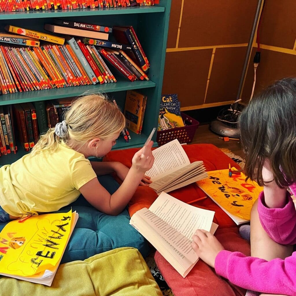 Second graders lay in reading corner at part time school.