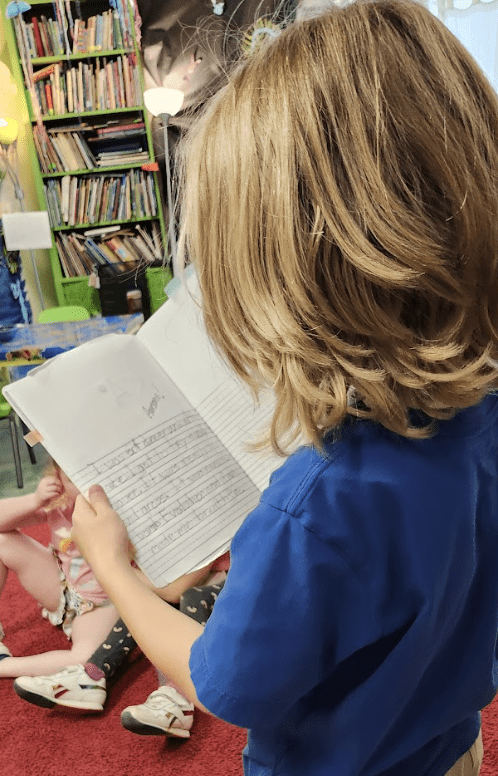 Kindergarten student reads book to class at GT school.