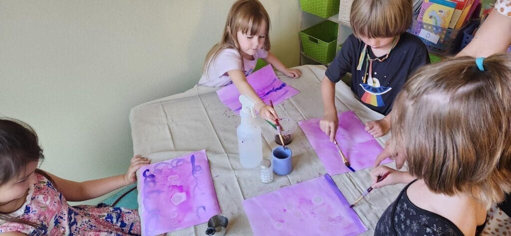 Four elementary children sit at a table painting