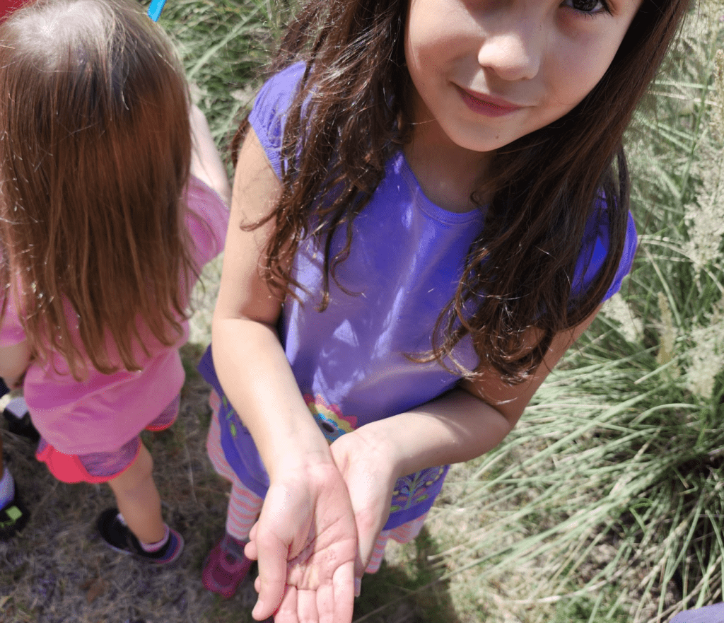 Kindergarten student displays what she found outdoors at STEM school in Austin.