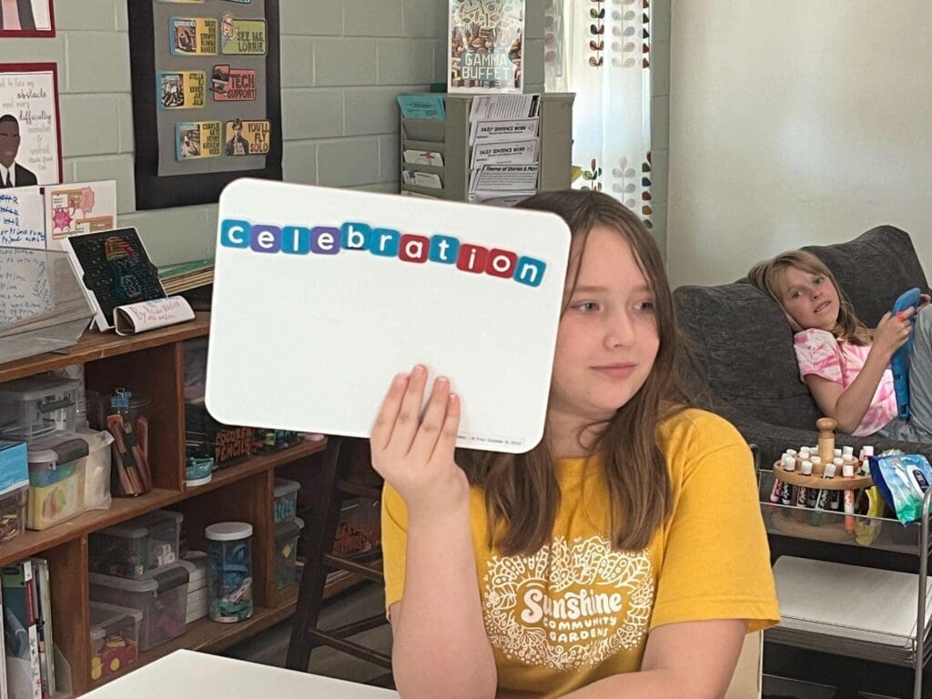 Fourth grade student holds up spelling word at hands on school.