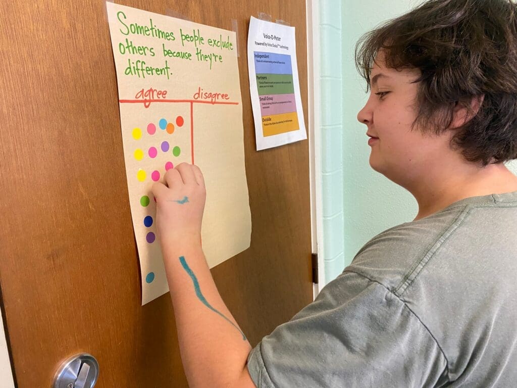 Seventh grade student writes on paper on wall at alternative middle school.