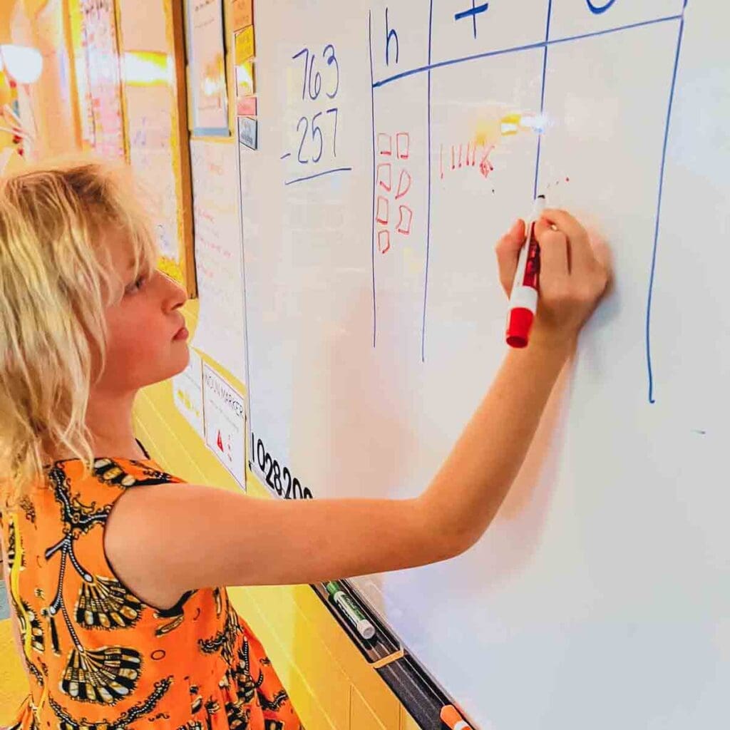 Third grade student works on STEM math problem at board.