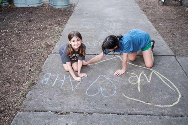Two elementary children draw with chalk at micro school in Austin.