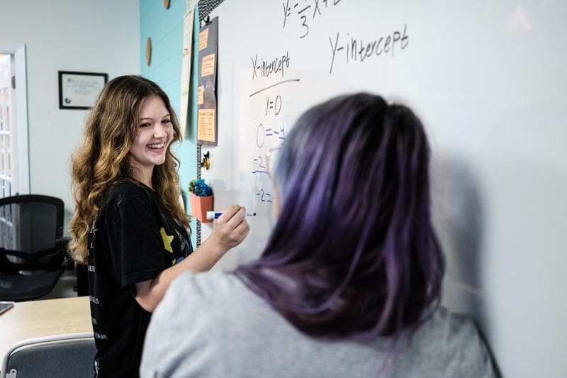 Middle school girl works at board doing STEM math.