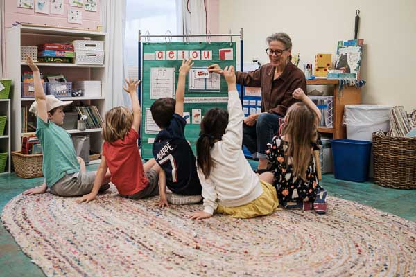 Kindergarten teacher demonstrates phonics concept in small class.