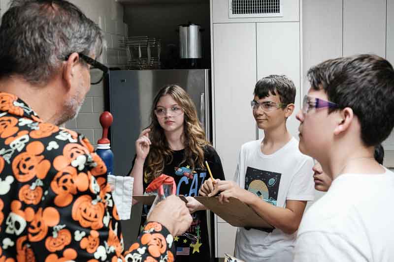 academics - making learning fun Teacher demonstrates science theme at part time school.