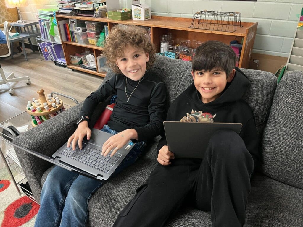 Two fourth graders work on couch at micro school in Austin