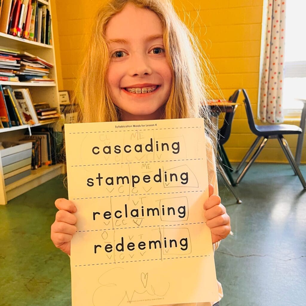 Micro school elementary student holds up language arts work proudly.