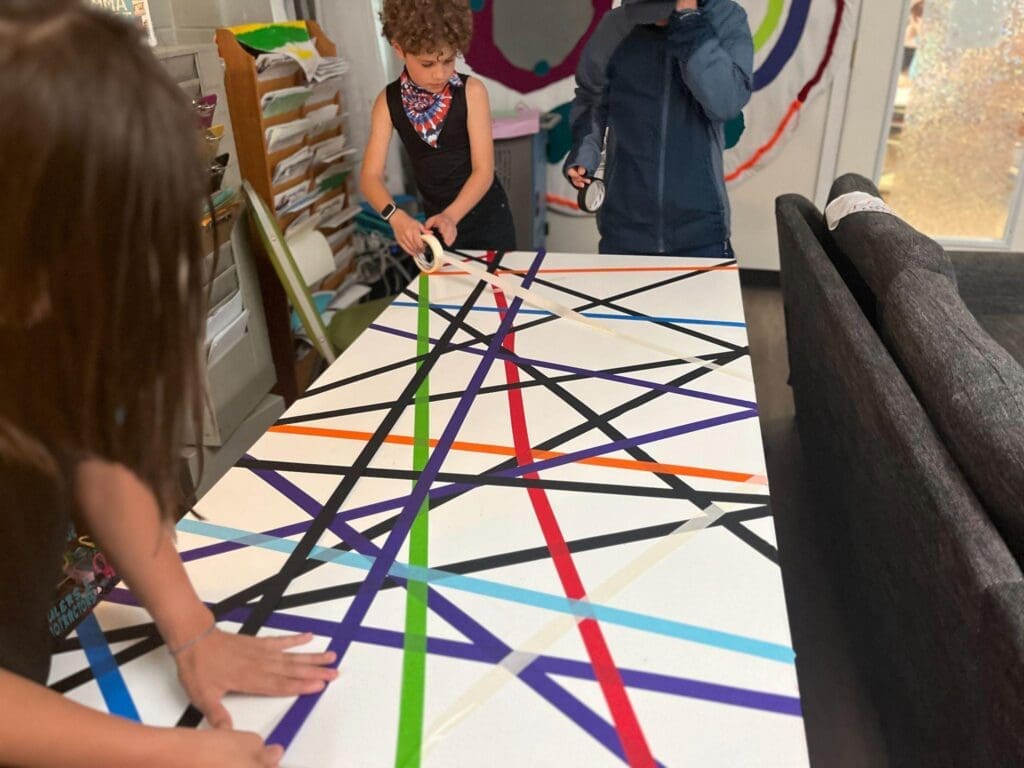 Students use tape on table at STEM school in Austin.