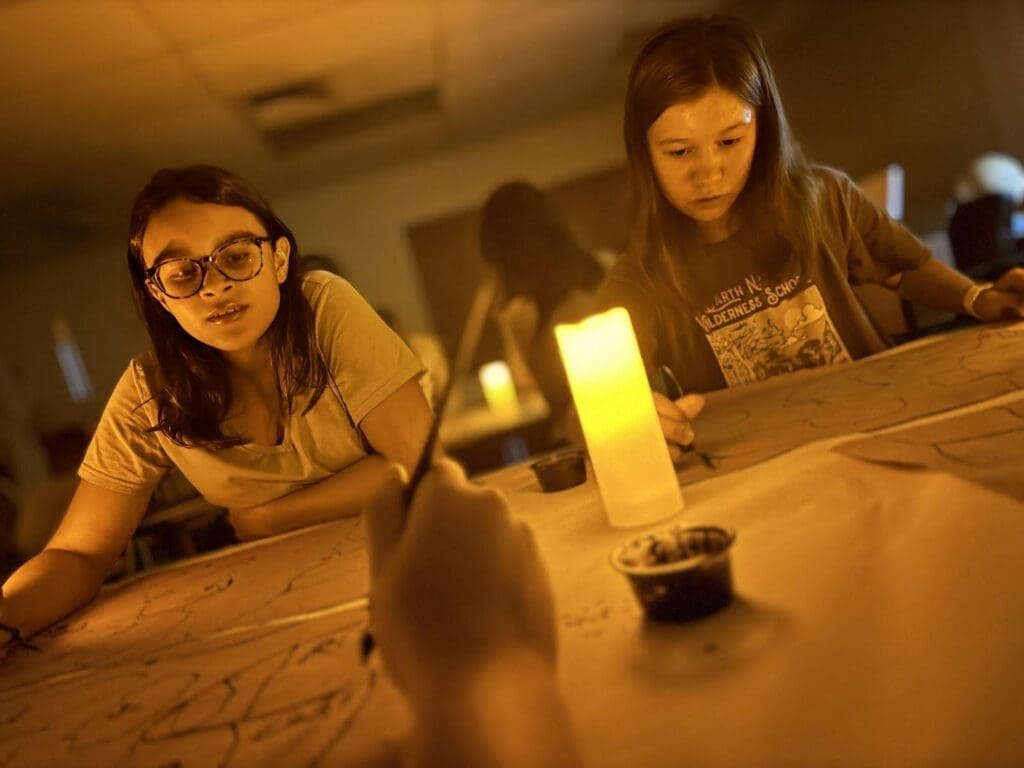 Two middle school girls work over candlelight at part time school.