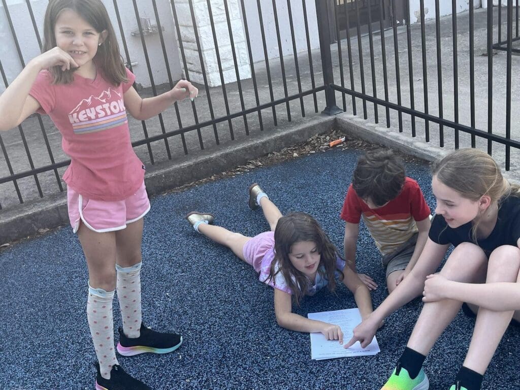 Second grade students work together on assignment on playground at micro school.