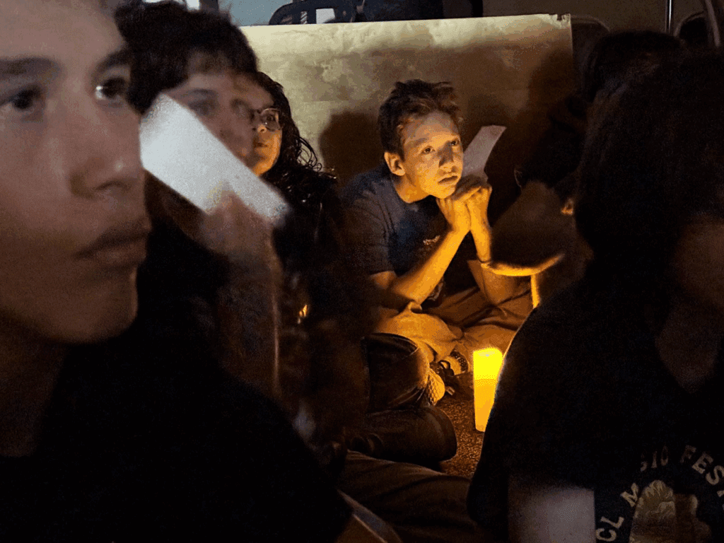 Middle school students sit around candle at school with small class size.