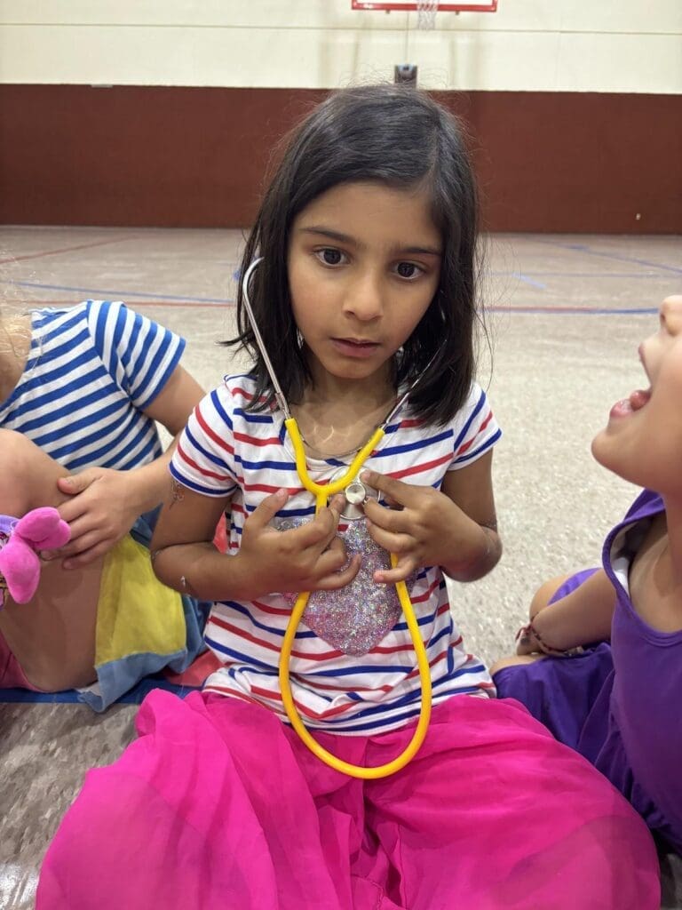 Kindergarten student uses stethoscope at STEM school.