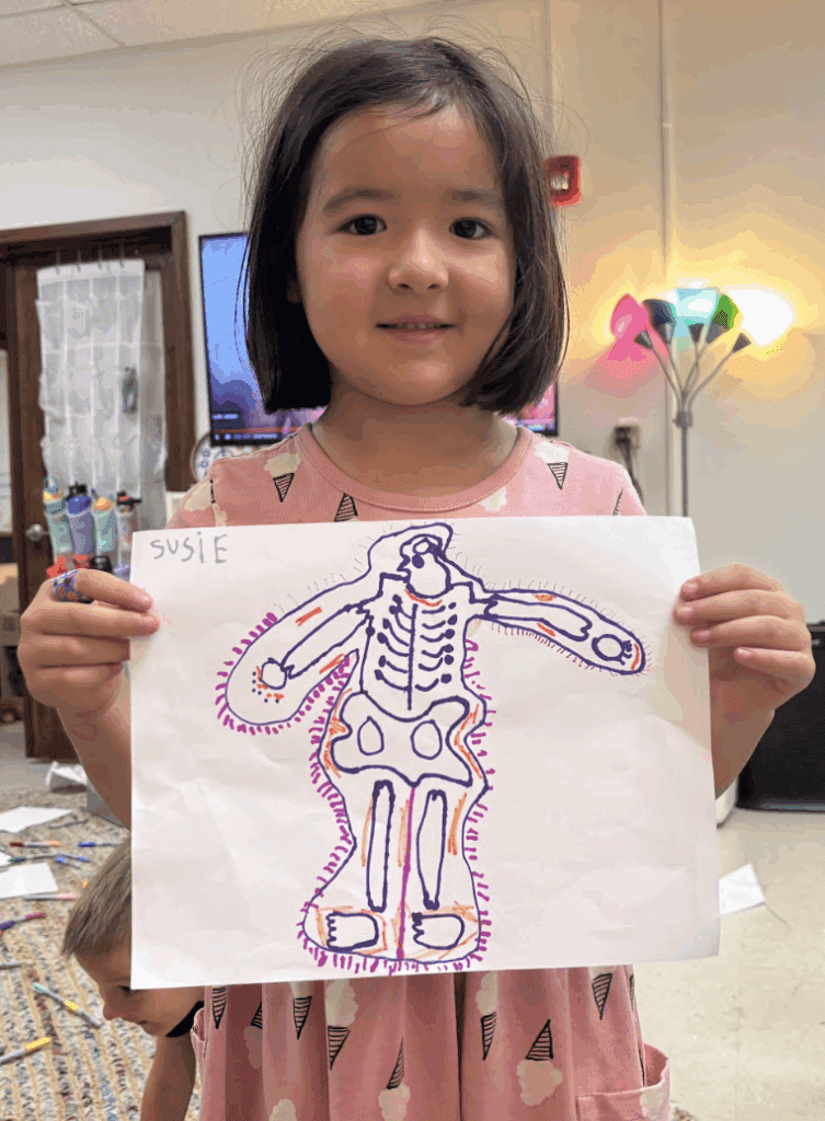 Kindergarten student displays skeleton drawing at project based school.