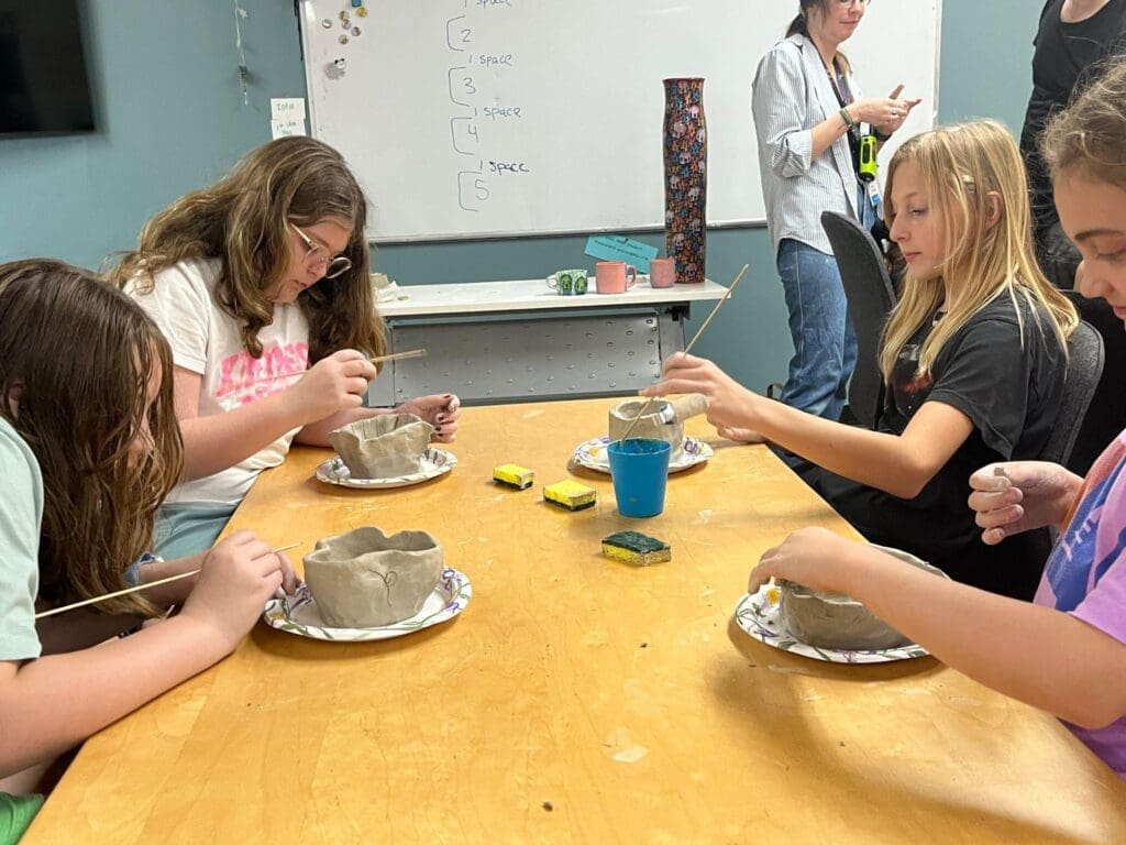 Four middle school girls work on clay project at school with small classes.