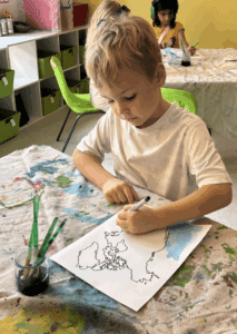 Kindergarten student paints geography at project based school.