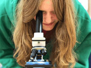 Middle school student uses microscope at micro school.