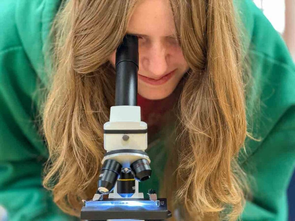 Middle schooler looks in microscope at STEM school in Austin.