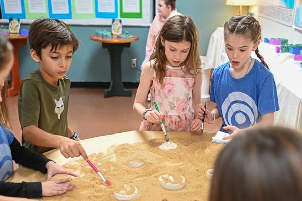 Elementary students explore fossils in sand at micro school in Austin.