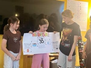 Three middle schoolers present report at project based school.