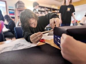 Middle schooler works on project at school with small classes.