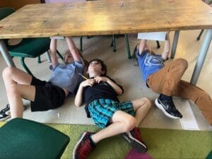 Three elementary students work under table at project based school.