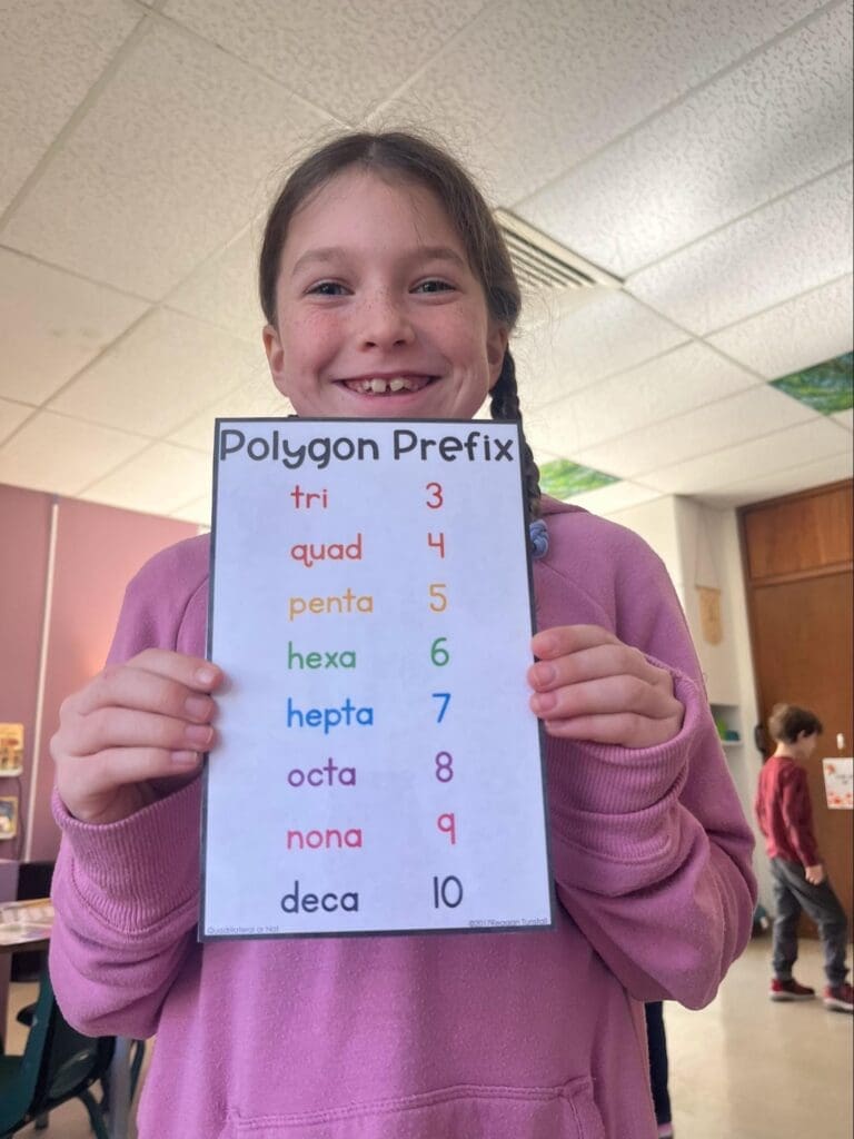 Elementary student holds up work at school with small classes.