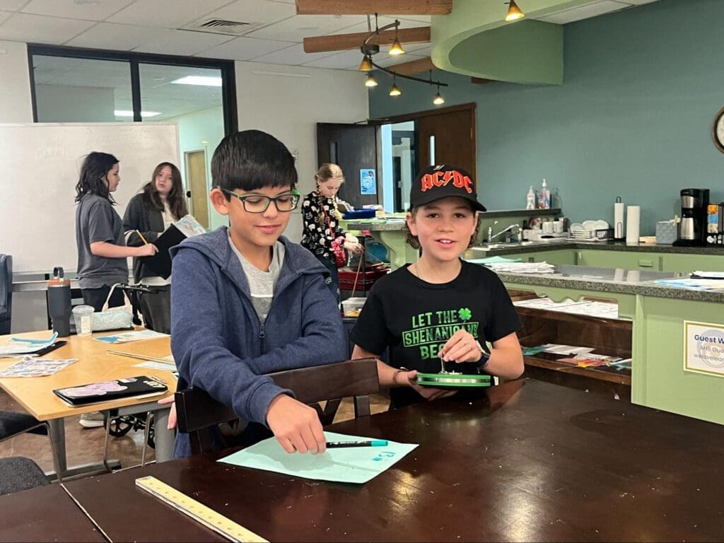 Two middle school students work at table together at project based school.