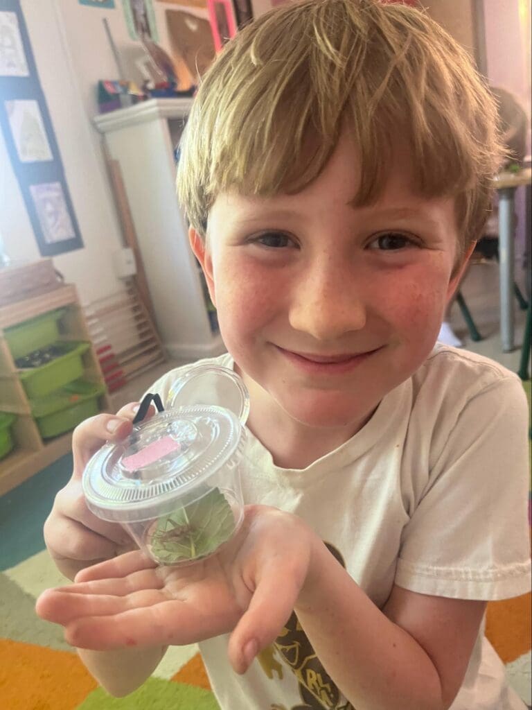 Elementary student proudly holds bug at project based school