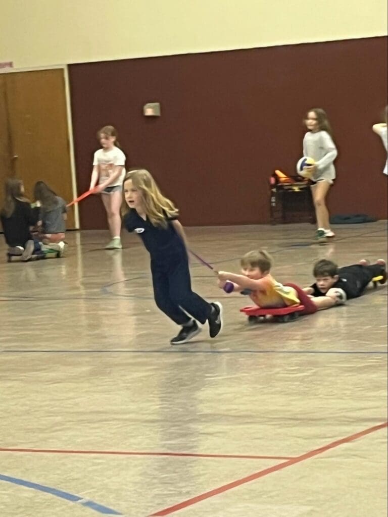 Elementary students play in gym at private school.