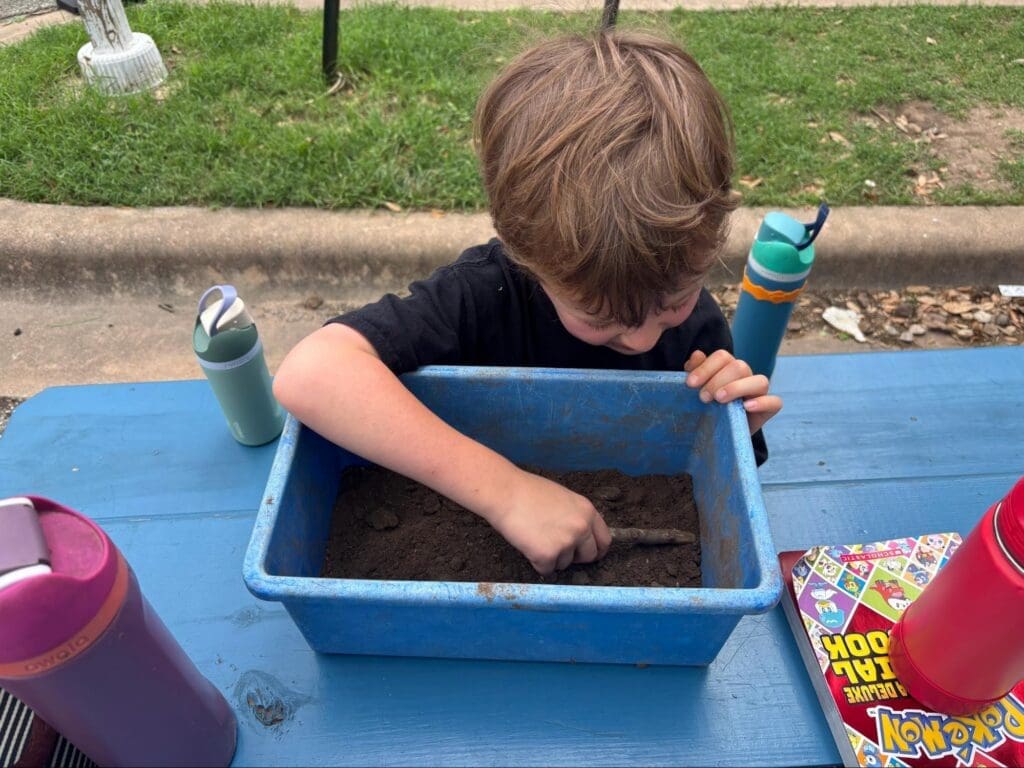 Kindergarten student works with dirt at half day school.
