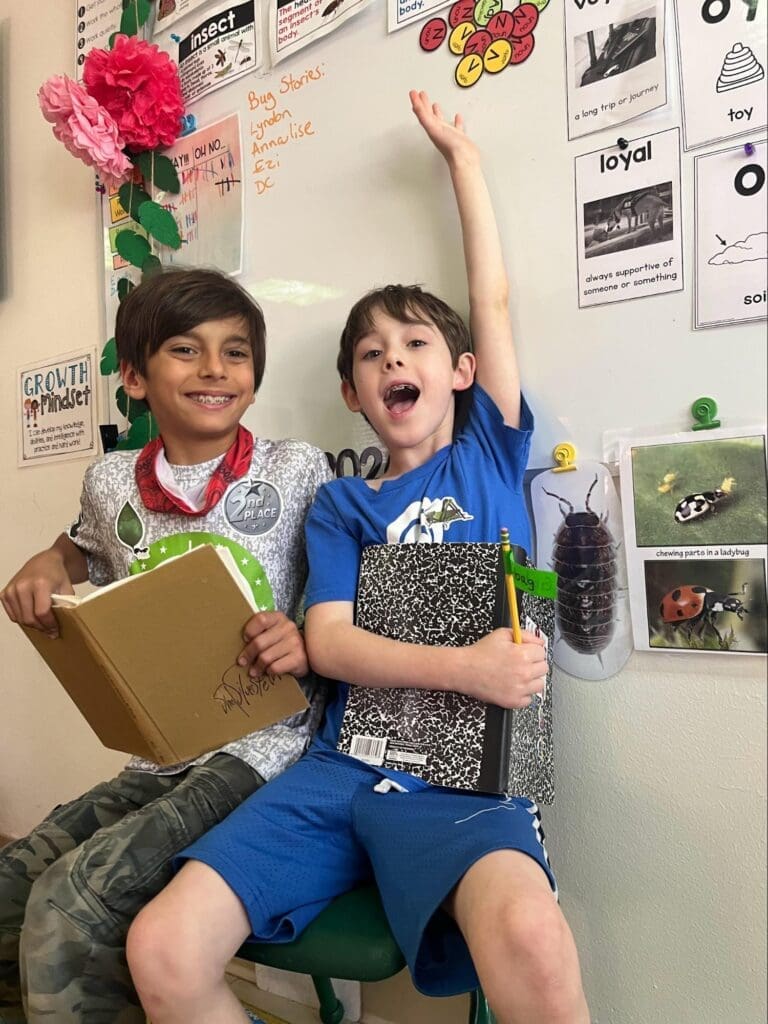 Two elementary boys read together at micro school.
